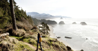 A woman hiking a path near the Oregon Coast with a Pacific Northwest trip